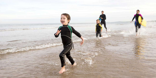 Family in wetsuits on a beach