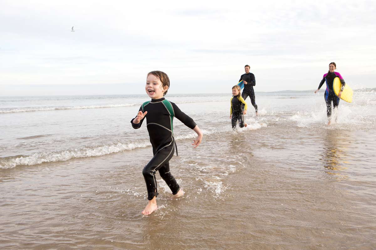 Family on the beach in wetsuits